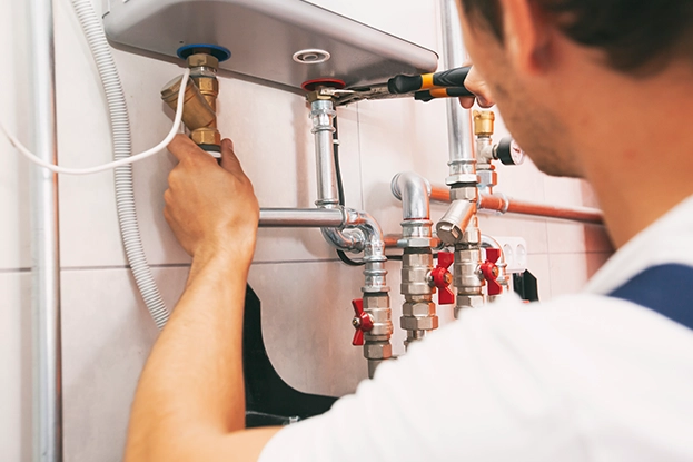 Two installers positioning new tall water heater tank in unfinished basement corner