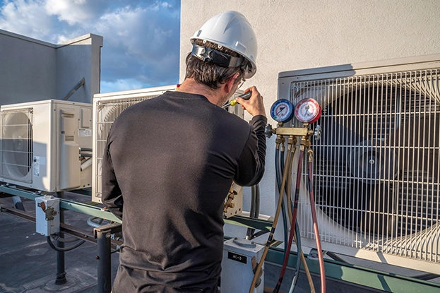 HVAC repair specialist testing outdoor air conditioning unit with digital multimeter